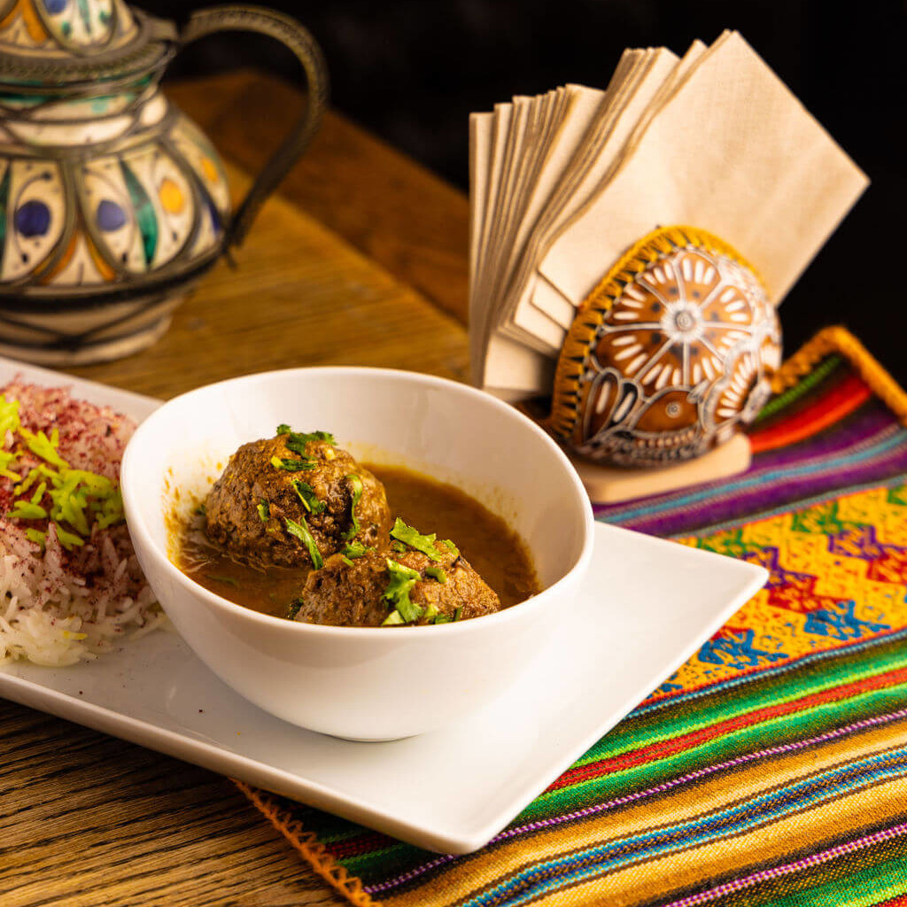 Boulettes de viande épicées et riz servi sur une nappe ethnique colorée pour une présentation chaleureuse et exotique.