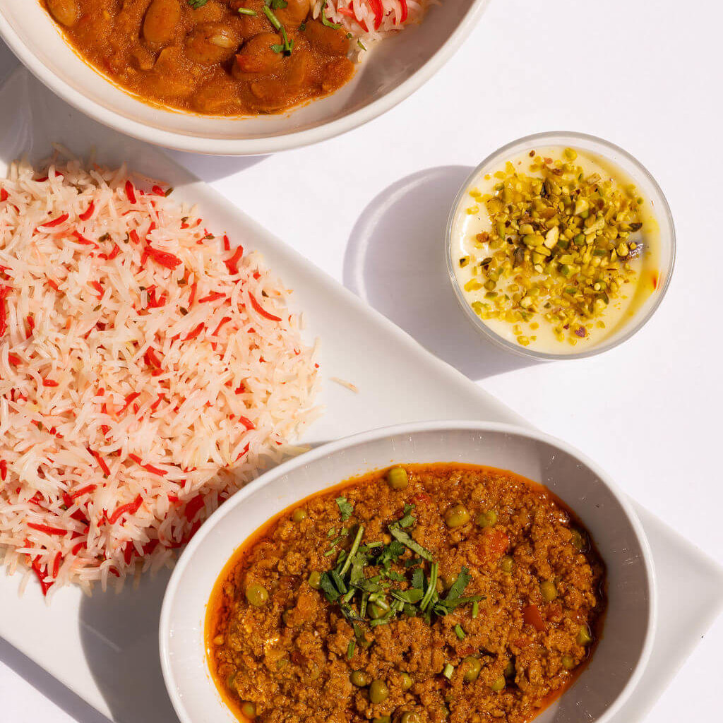 Assiette de curry épicé servi avec du riz parfumé, un dessert pistache et coriandre en garniture pour une expérience culinaire authentique.