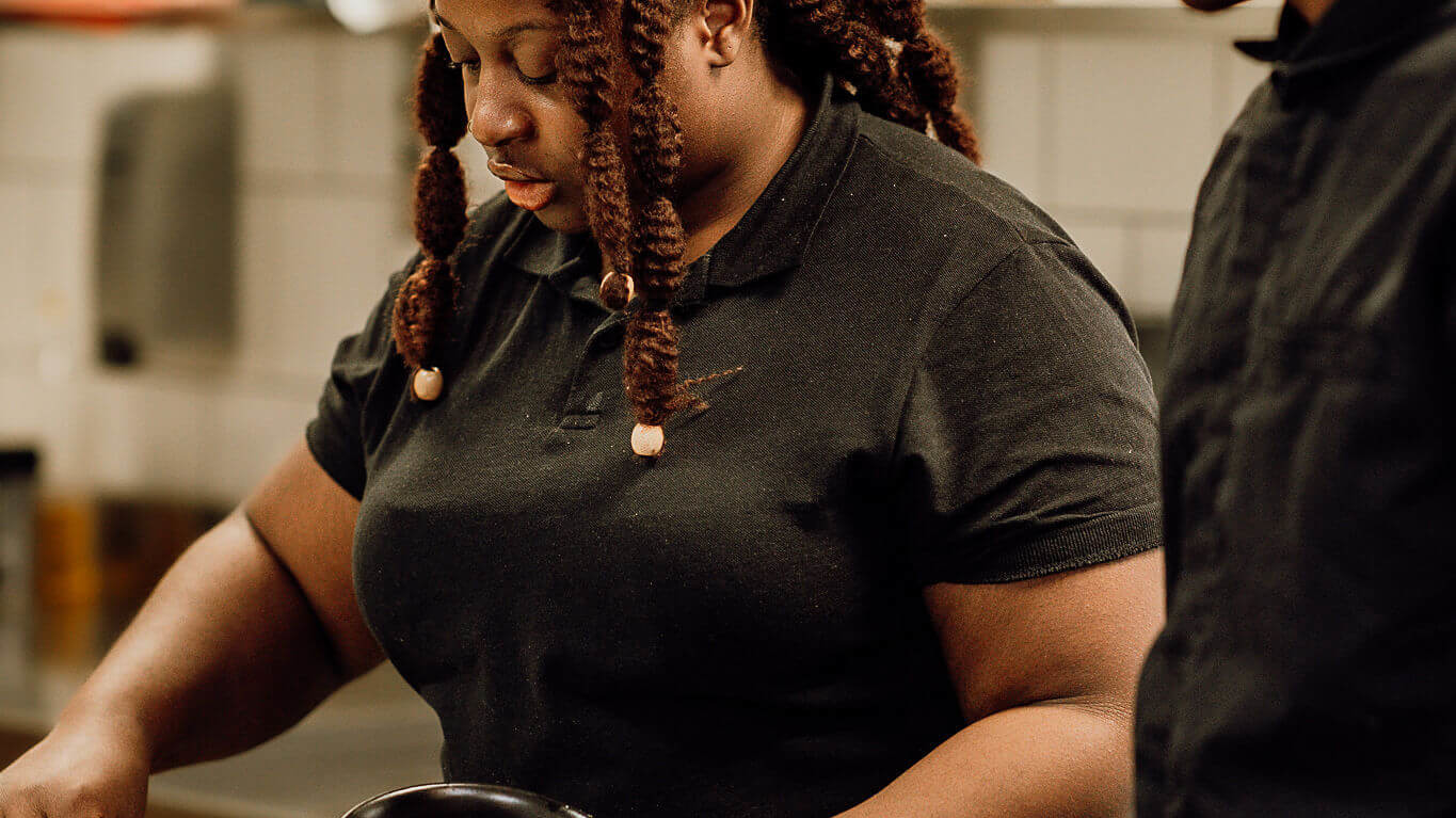 Deux cuisiniers concentrés en cuisine, préparant soigneusement un plat dans une ambiance professionnelle et collaborative.