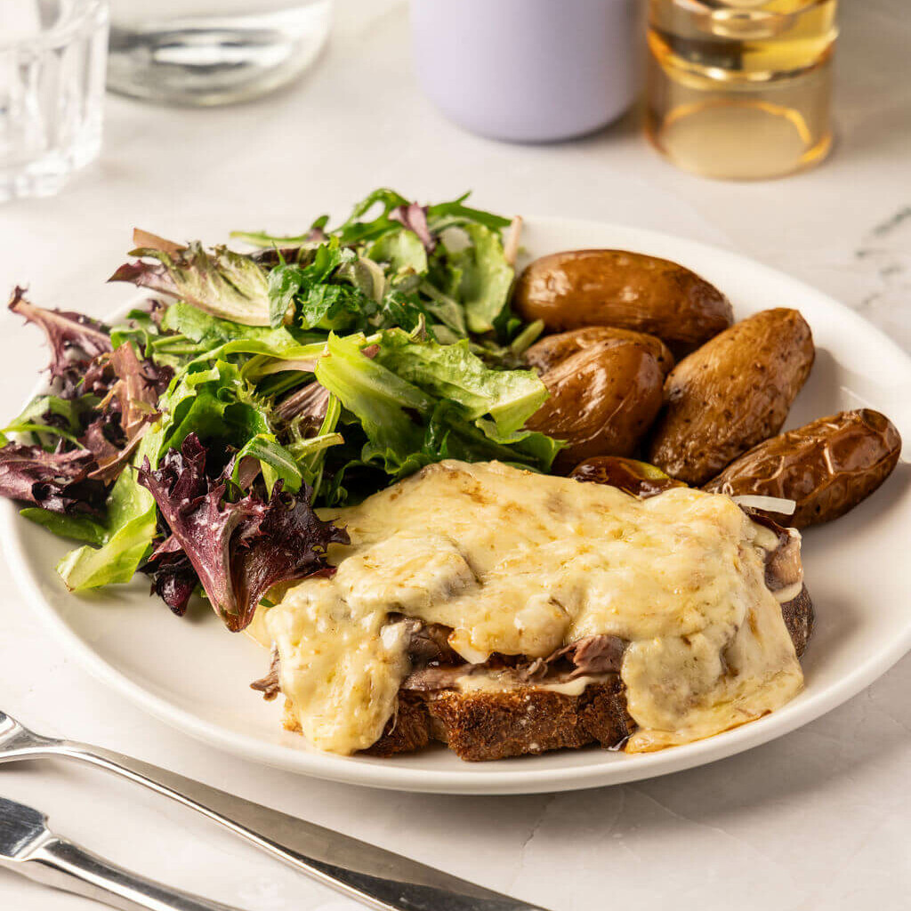 Tartine gratinée au fromage avec pommes de terre rôties et salade fraîche – repas savoureux et réconfortant.