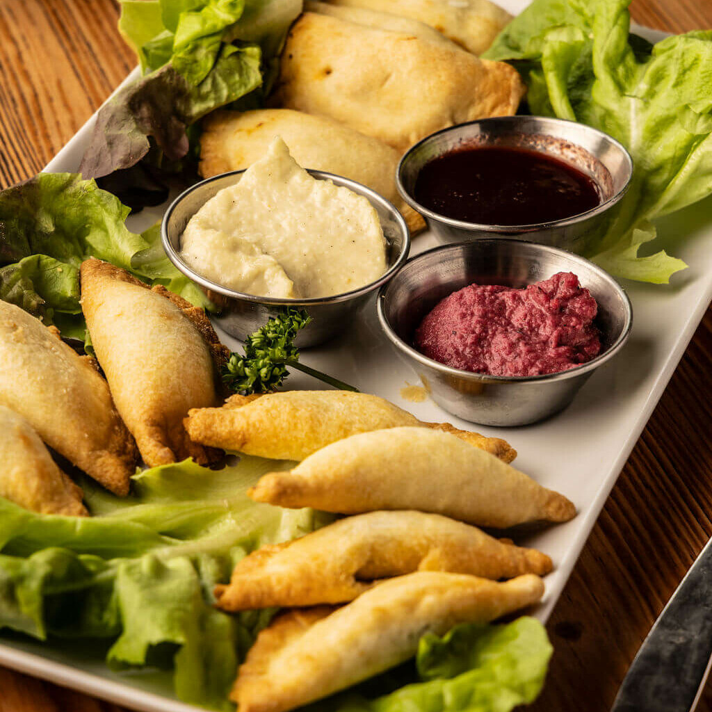 : Assiette de samoussas maison avec trio de sauces colorées et salade verte – cuisine africaine