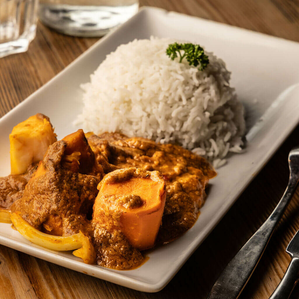 Plat sénégalais Mafé aux légumes et riz basmati blanc servi dans une assiette rectangulaire