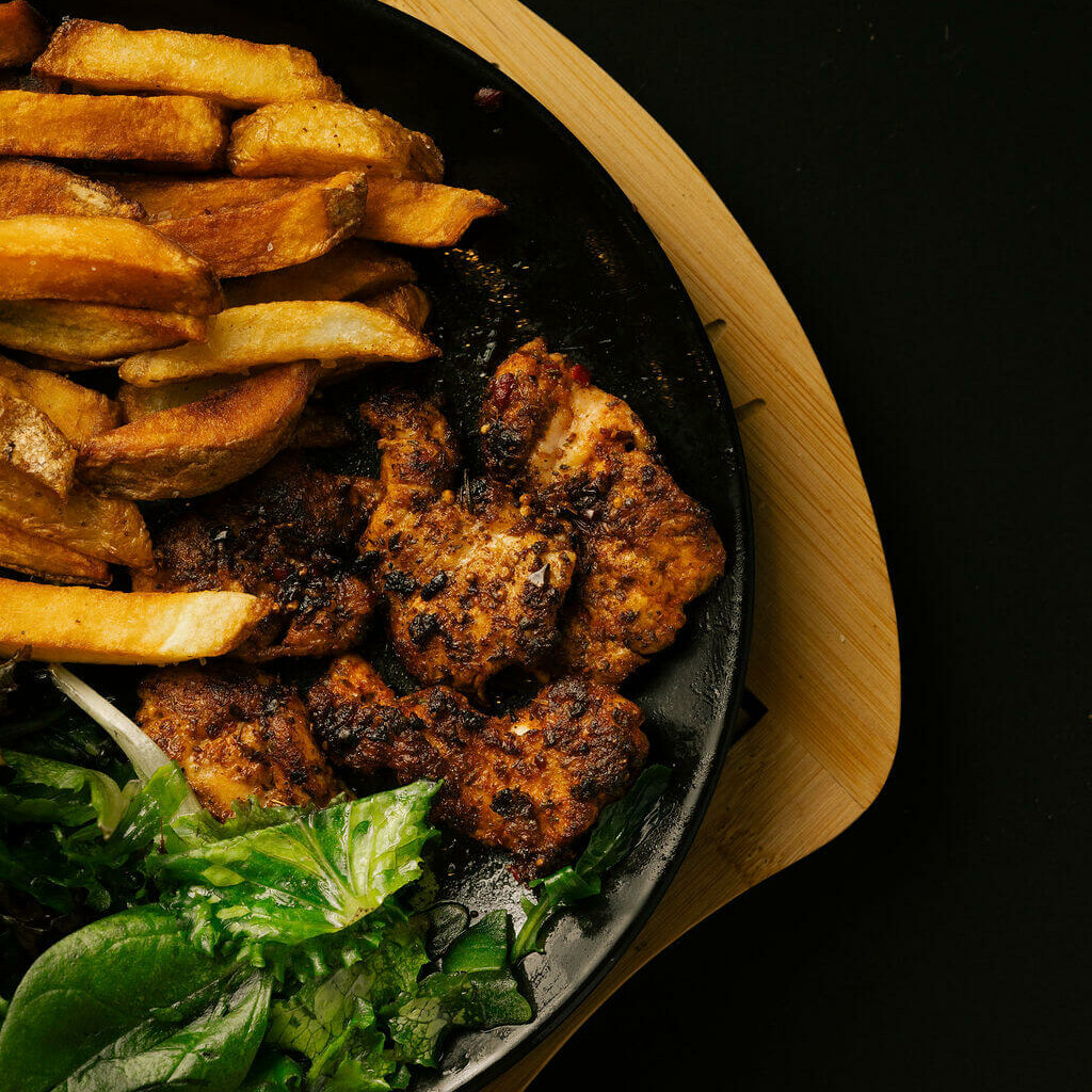 Assiette de poulet mariné grillé, frites maison et salade verte.