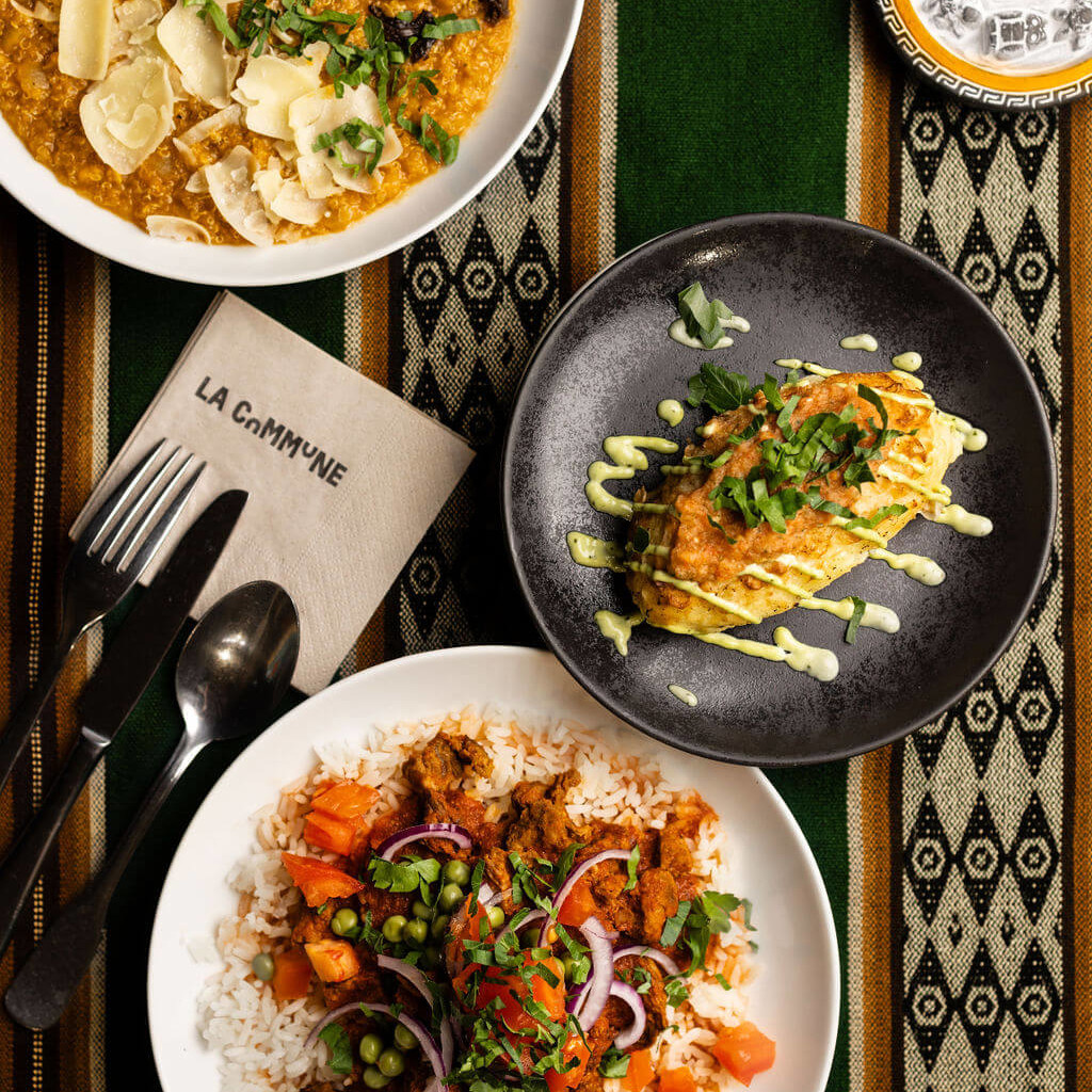 Trio de plats traditionnels andins incluant de la quinoa, des pommes de terre, et du riz épicé, sur une nappe aux motifs ethniques.