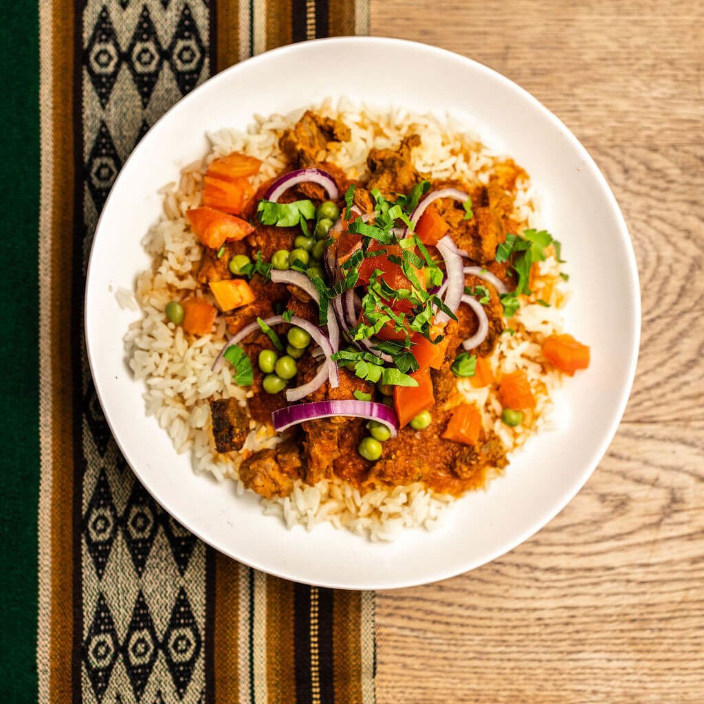 Plat de riz avec légumes colorés et épices, inspiré de la cuisine andine, pour une expérience culinaire riche en saveurs.