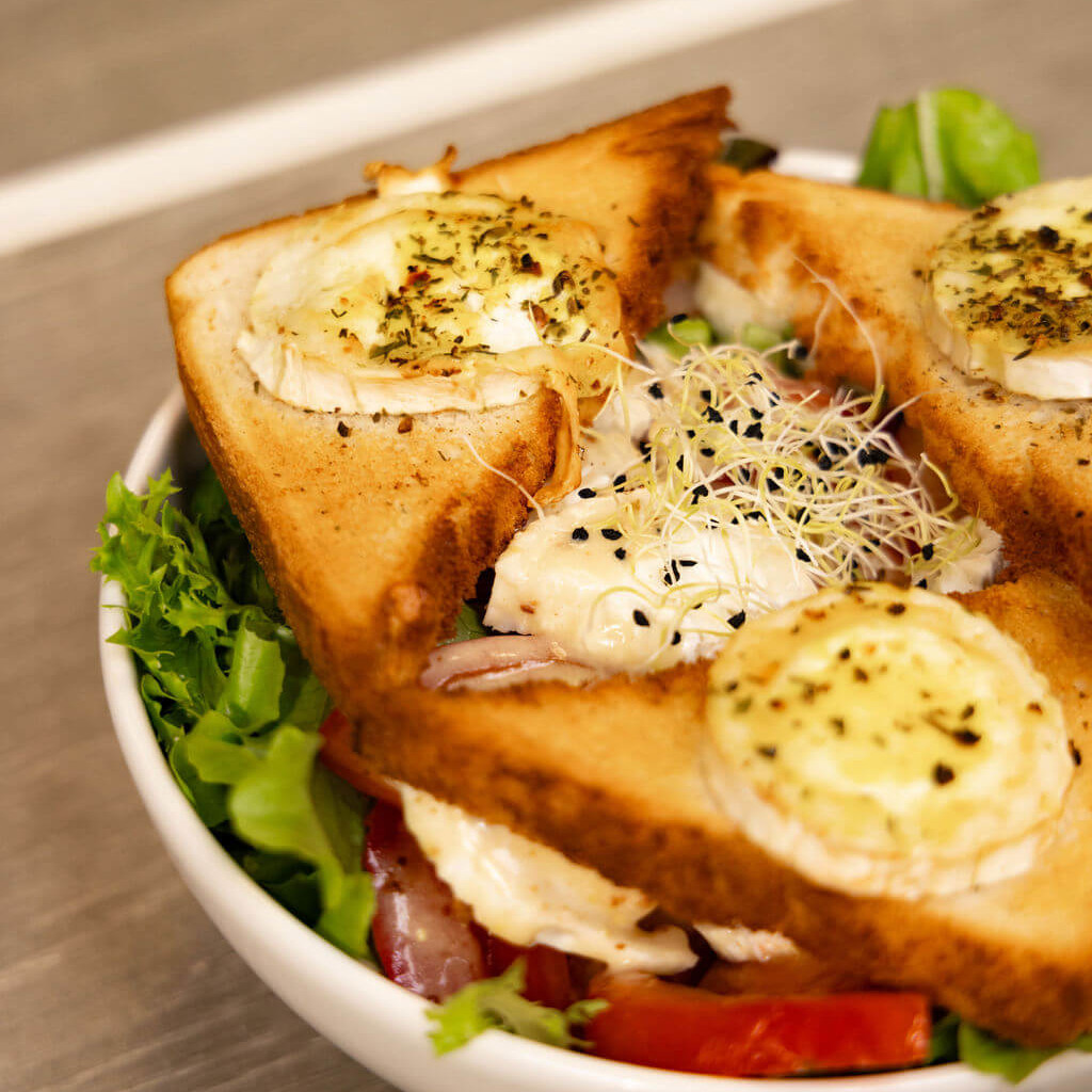 Salade verte garnie de toasts de fromage de chèvre fondu et pousses fraîches pour un goût authentique.