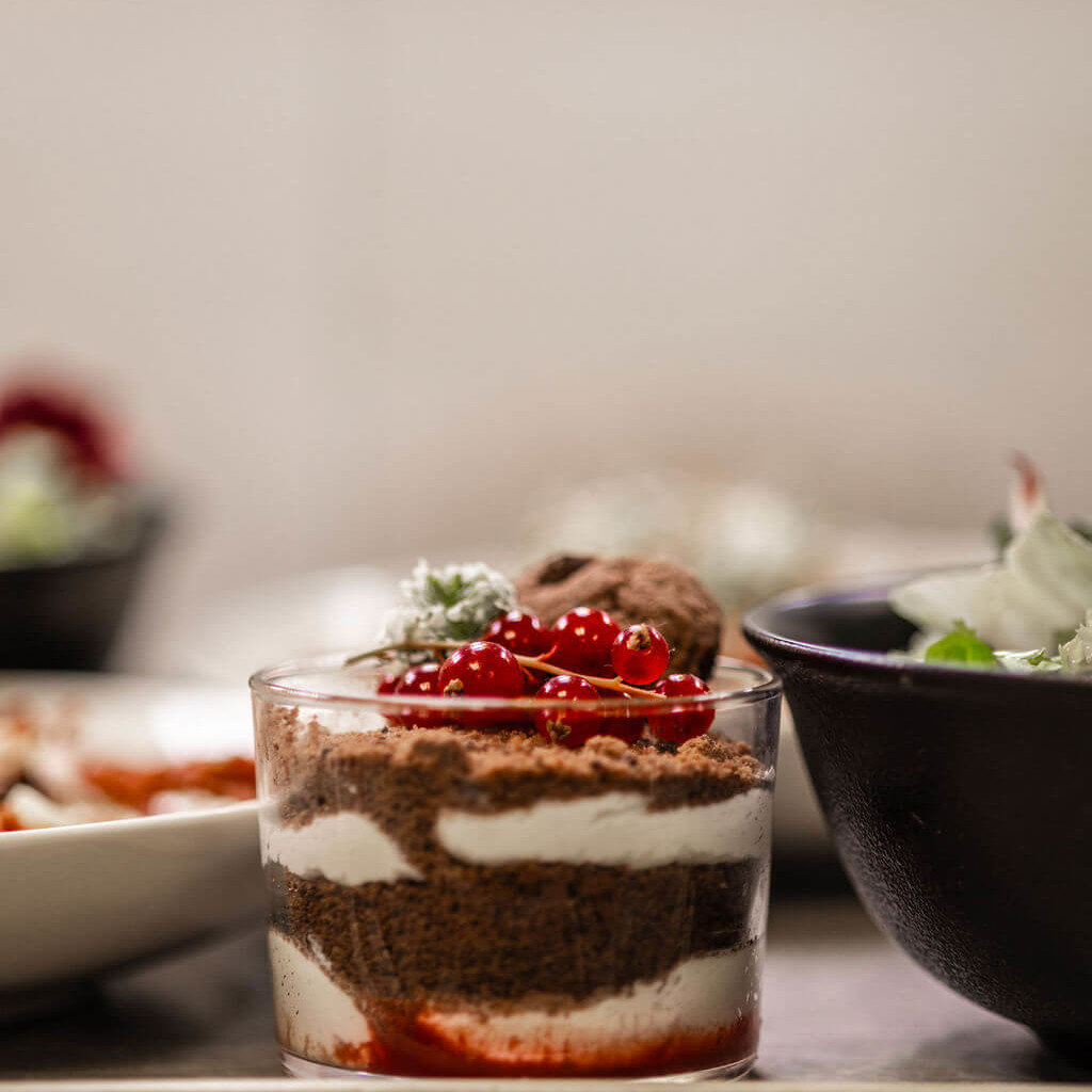 Verrine de dessert chocolaté avec couches crémeuses et décoration de groseilles fraîches.