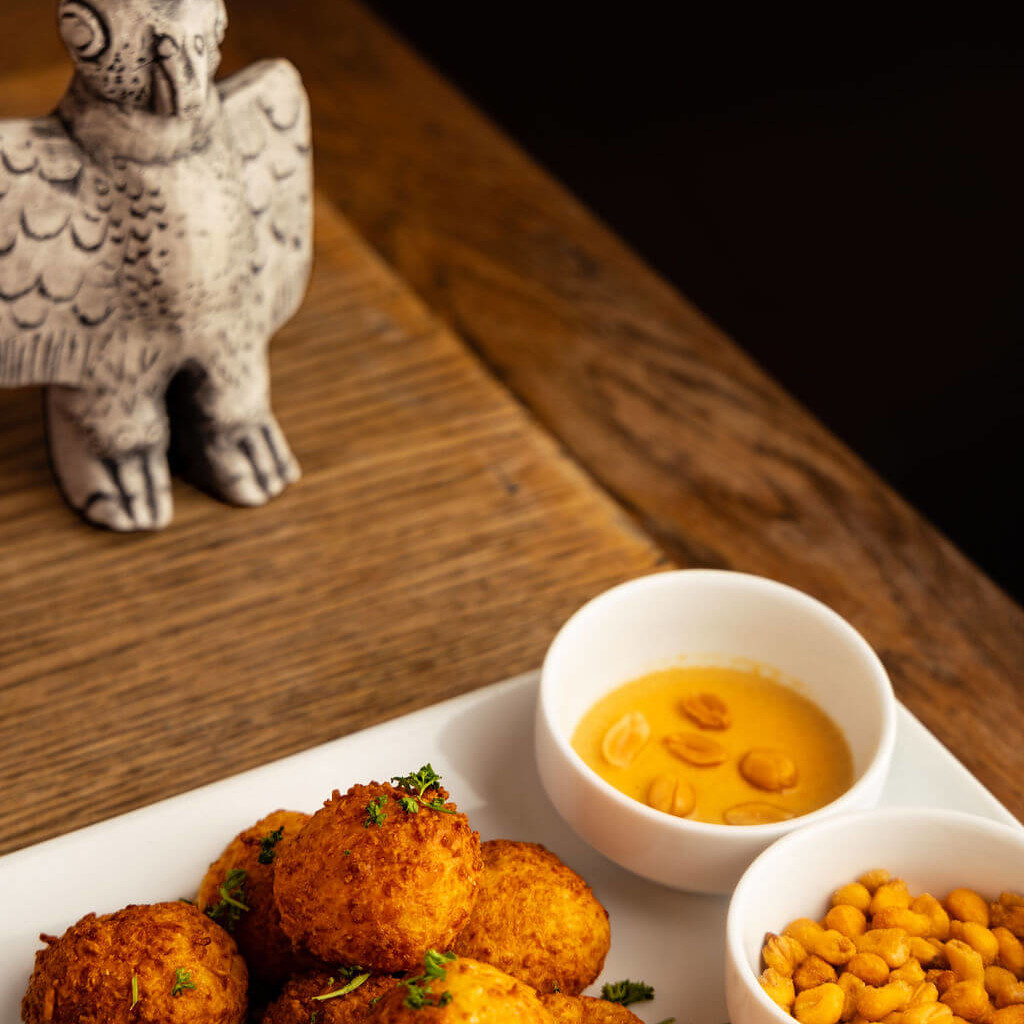 Croquettes dorées servies avec deux sauces et pois croquants, parfaites pour un apéritif aux influences péruviennes.