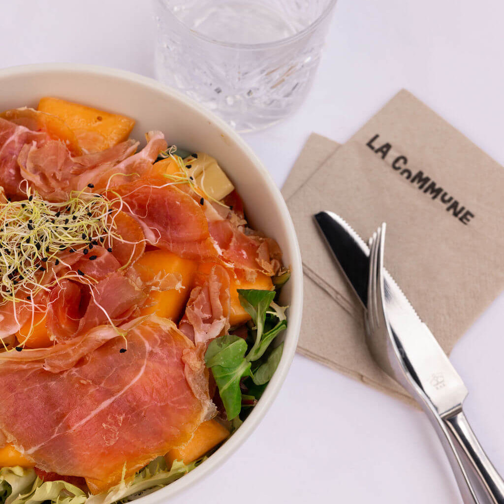 Salade estivale avec melon sucré, jambon de pays et jeunes pousses pour une touche colorée.