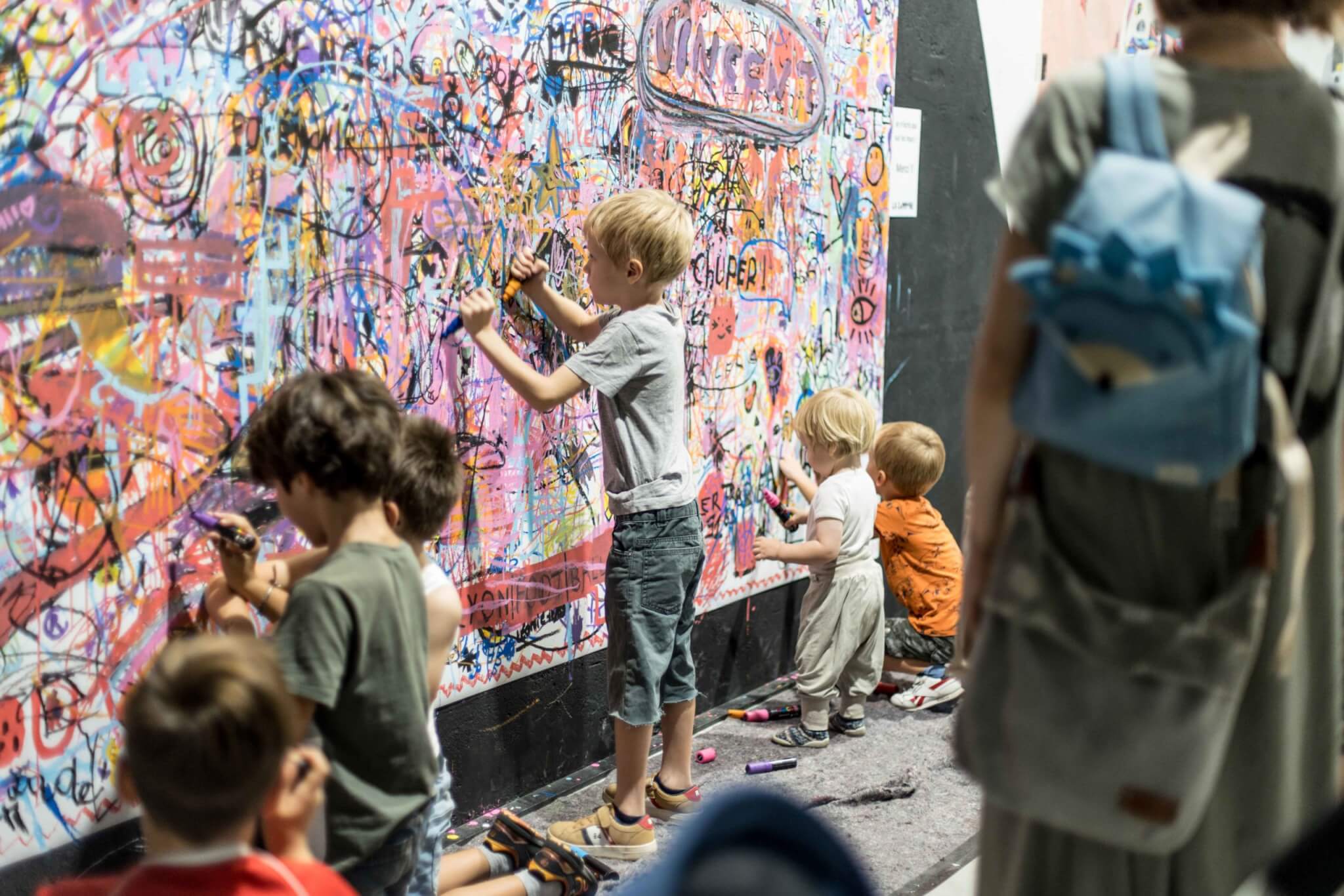 Une scène où plusieurs enfants s'amusent à dessiner sur un mur, libérant leur créativité avec des couleurs vives.