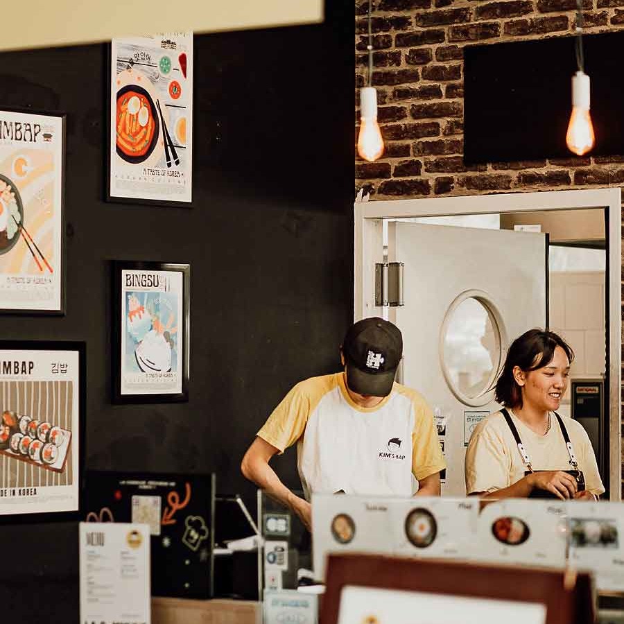 Restaurant Kim's Bap, spécialisé dans la cuisine coréenne, avec des affiches colorées et des serveurs en action.